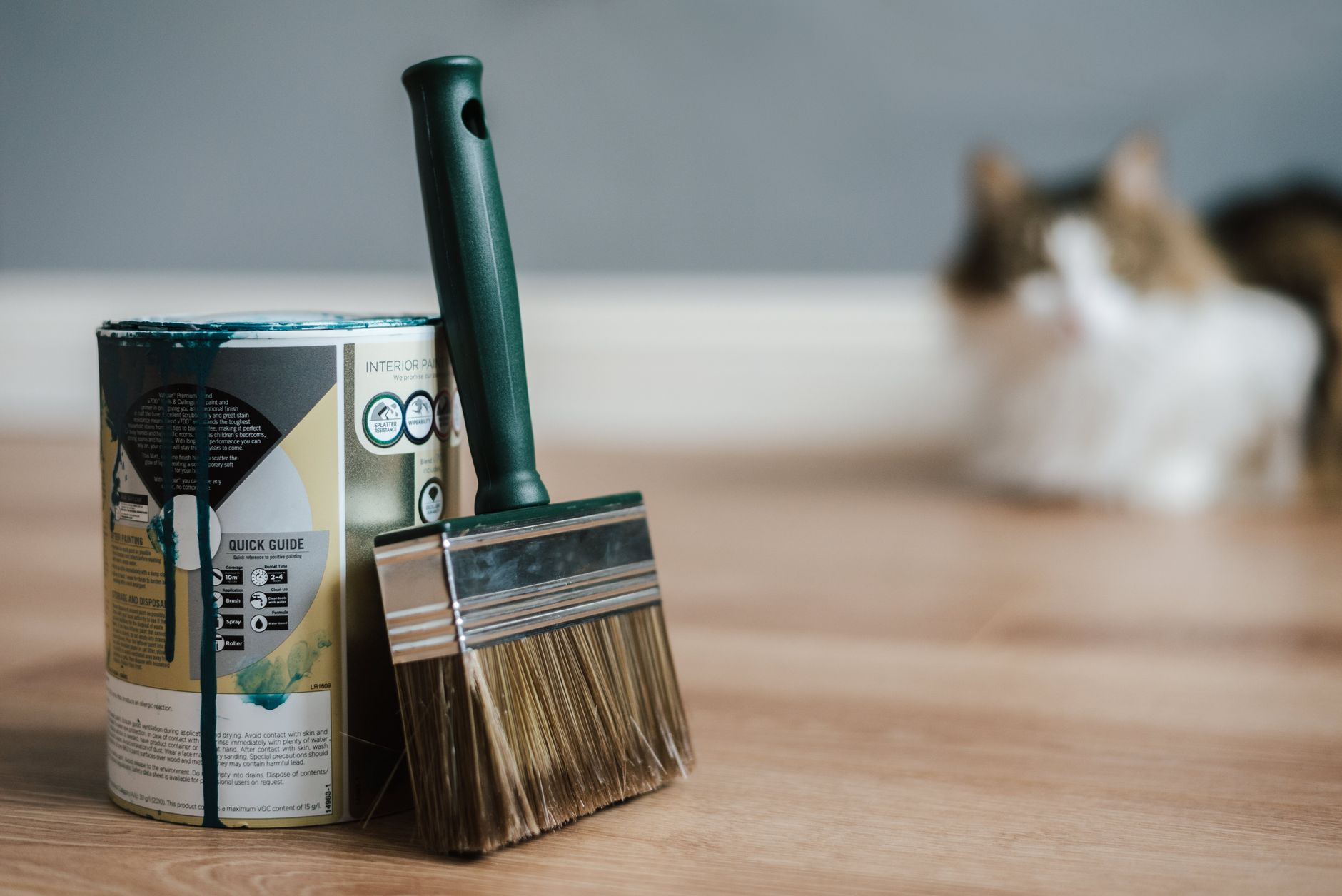 Professional paint brush near metal can with information and dirty flows on parquet in house in Carlsbad, CA