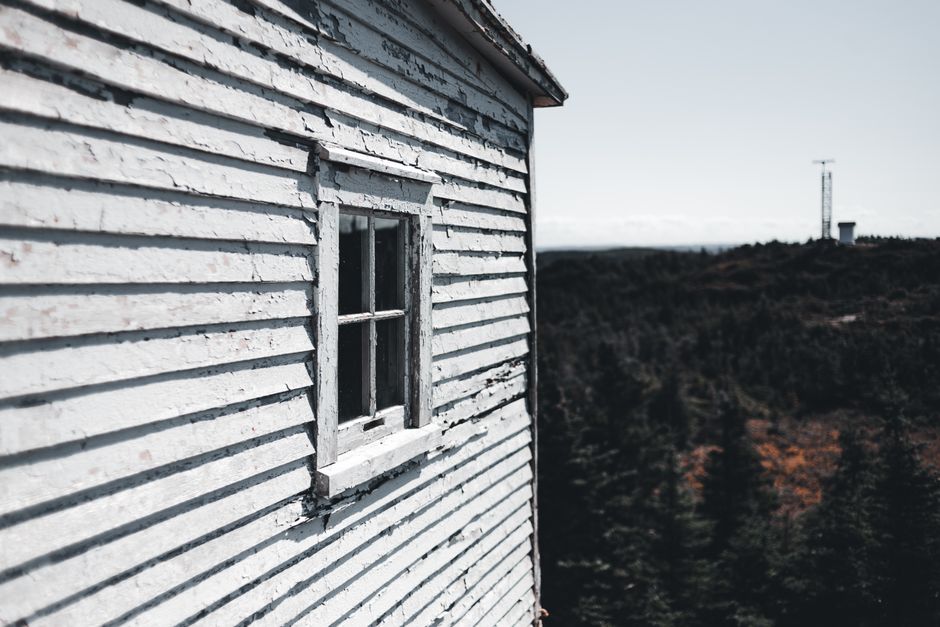 A weathered wooden house with peeling paint on its siding.