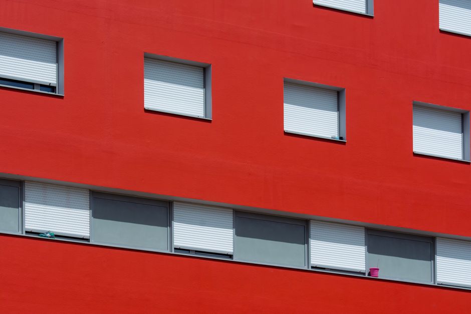 A house with red painted walls and closed shutters.